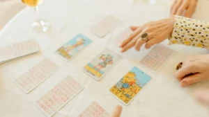 Pessoas participando de uma consulta de tarot com cartas abertas e viradas sobre uma mesa clara.