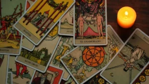 Cartas de tarot espalhadas sobre uma mesa de madeira ao lado de uma vela acesa