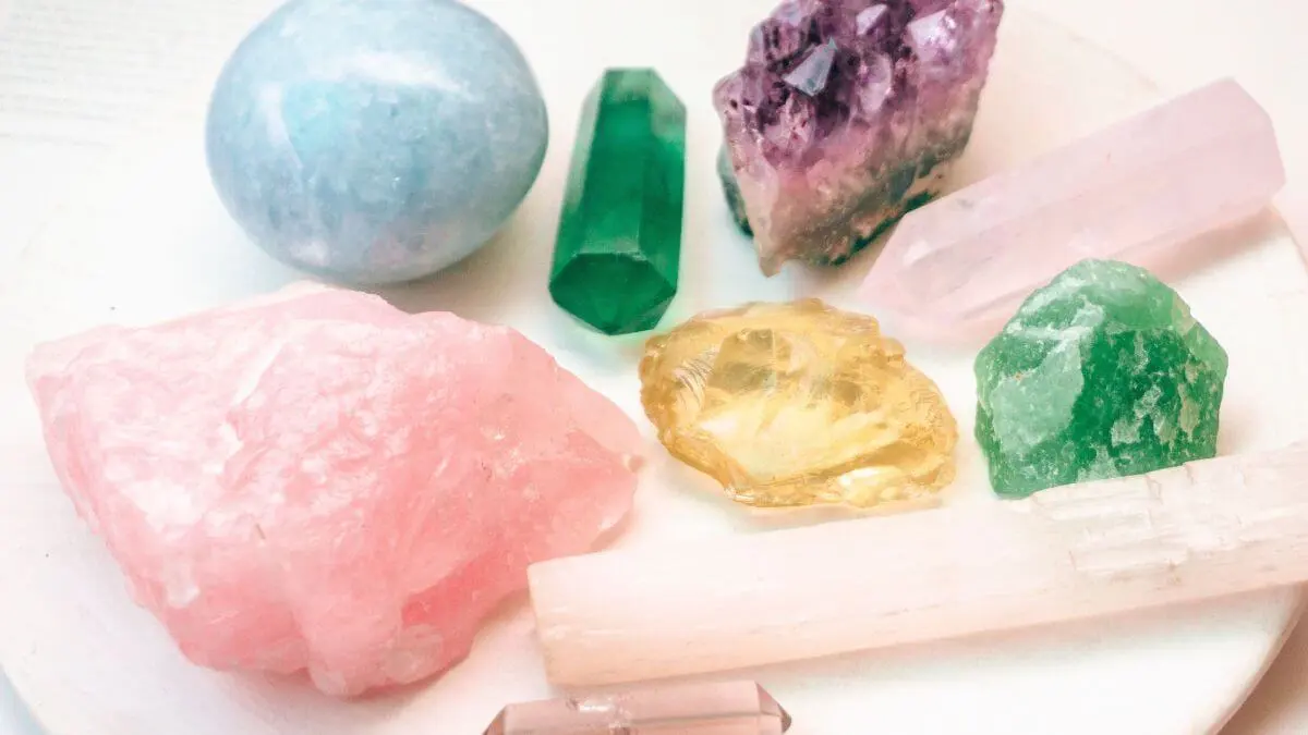 Conjunto de cristais coloridos, incluindo quartzo-rosa, ametista, pedras verdes, cristal amarelo e selenita.