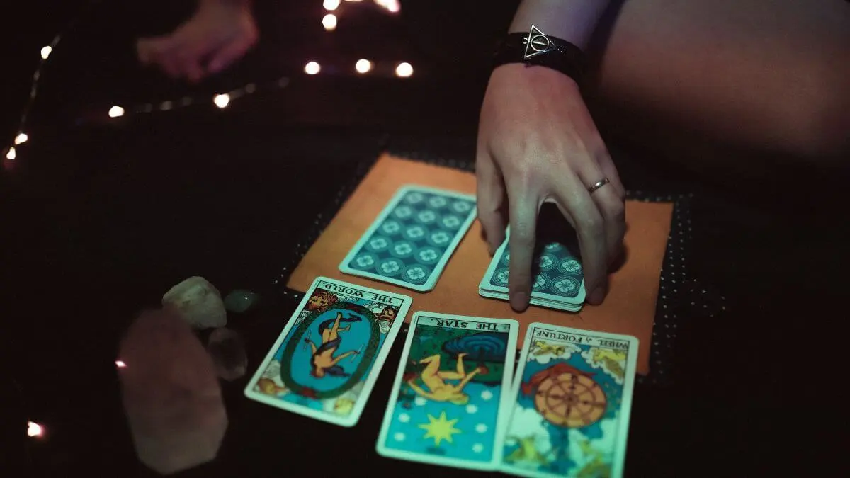 CARTAS DE TAROT ESPALHADAS SOBRE MESA COM VELAS E CRISTAIS
