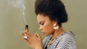 Mulher segurando um palo santo aceso durante ritual de limpeza espiritual