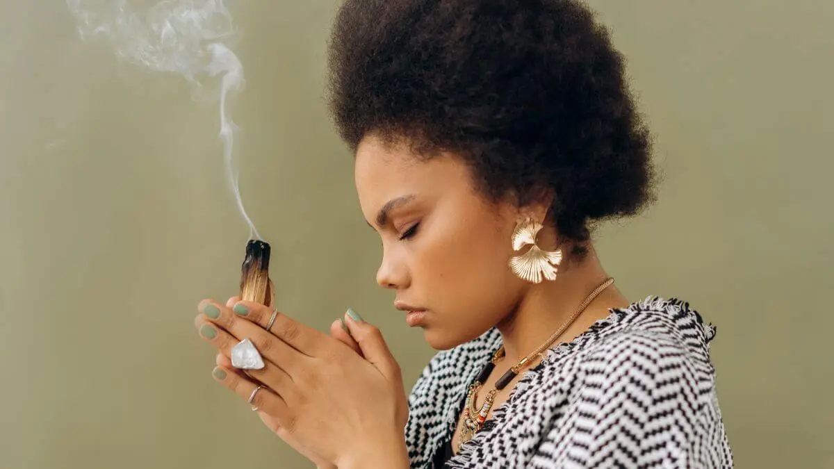 Mulher segurando um palo santo aceso durante ritual de limpeza espiritual