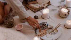 Pessoa preparando um ritual espiritual com velas acesas, cristais, incenso e ervas.