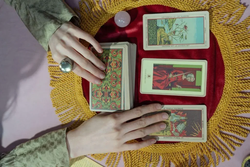MÃOS SEGURANDO CARTAS DOS ARCANOS MAIORES DO TAROT SOBRE MESA MÍSTICA
