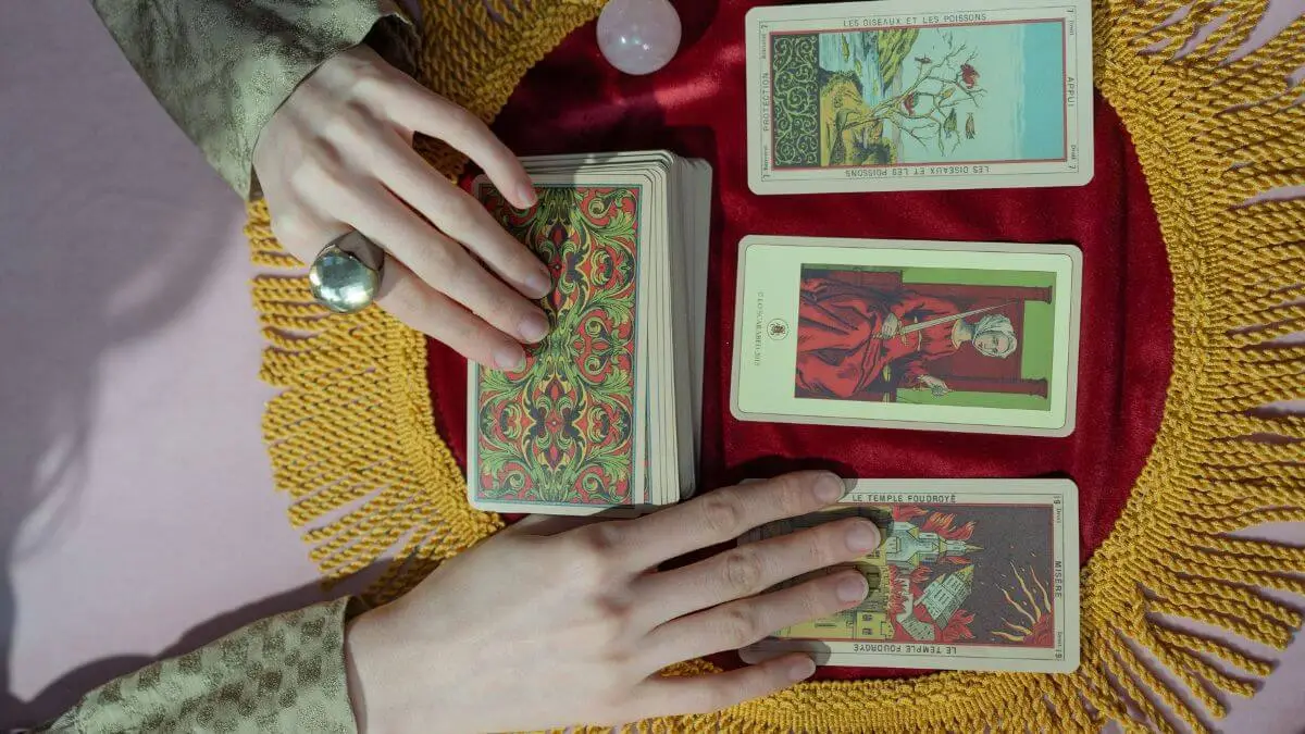 Cartas de Tarô ao lado de caderno usado para escrever perguntas para uma leitura