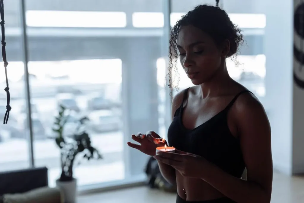 Mulher acendendo uma vela durante momento de meditação, conexão espiritual e autocuidado.